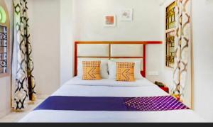 een slaapkamer met een bed met oranje en paarse kussens bij SAROVAR INN in Chennai