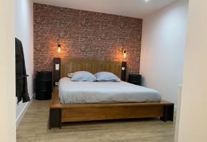 - une chambre avec un lit et un mur en briques dans l'établissement Cosy 2 Pièces Vue Mer Aux Parfums de Grasse, à Grasse
