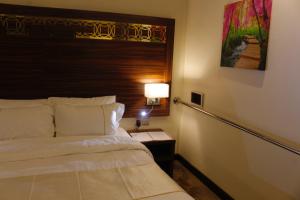 1 dormitorio con 1 cama y 1 mesa con lámpara en Central Park Hotel Bisha en Qal'at Bishah