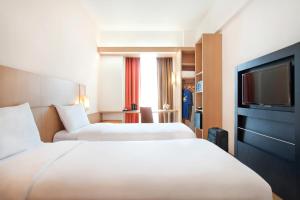 a hotel room with two beds and a flat screen tv at ibis Marseille Provence Aéroport in Marignane