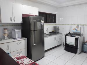 a kitchen with a stainless steel refrigerator and a stove at Linda Casa, 3 quartos, acomoda 10 pessoas, há 1,5 km da praia da Enseada in Guarujá