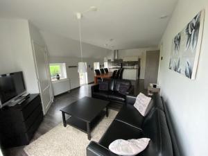 a living room with a black couch and a table at Bed and breakfast de Boerderij in Albergen