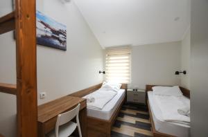 a small room with two beds and a desk at Hostel Atrijum in Kladovo