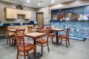 a restaurant with wooden tables and chairs and a kitchen at Rodeway Inn Carrollton I-35E in Carrollton