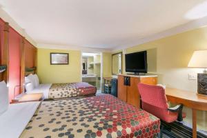 a hotel room with two beds and a desk and a television at Econo Lodge Frederick I-70 in Frederick