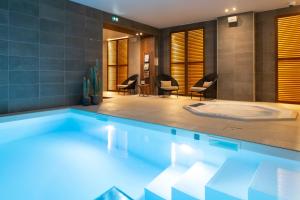a swimming pool in a room with chairs at HÔTEL & SPA Panorama 360 in Mâcon