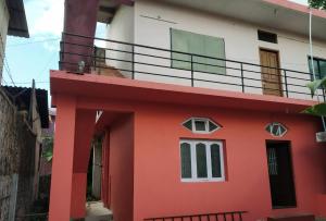 a red and white house with a balcony at Doctors Heritage Lodge in Sringeri