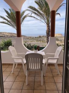 a porch with white chairs and a view of the desert at Apartamento en La Pared Fuerteventura vista mar in Pájara