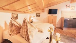 ein Schlafzimmer mit einem Bett mit Kissen und einem TV in der Unterkunft Stubaier Bauern Appartement in Telfes im Stubai