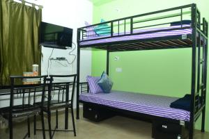 a room with two bunk beds and a table and a television at Tranquil AC Budget Room( Single, Family & Group) in Bhubaneshwar +8 photos