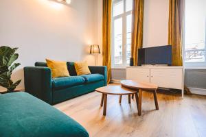 a living room with a couch and a table and a tv at Hyper centre - Cathédrale in Reims +8 photos