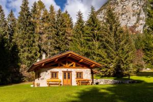 a log cabin in a field with trees and mountains at Baita Valon - Alpine Hideaway in Comano Terme