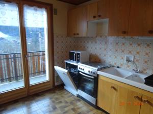 a kitchen with a stove and a sink and a microwave at Pic de la Corne in Abondance