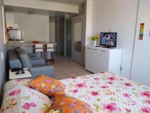 a room with a bed and a living room with a television at Farol da Barra 209 in Salvador