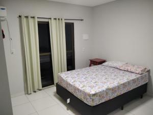 a bedroom with a bed and a window at Residencial Zé Buscapé in Bombinhas