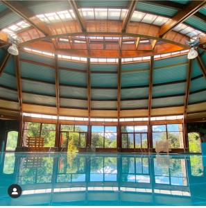 an indoor swimming pool with a large glass ceiling at Malalcahuello Thermal Hotel & Spa in Malalcahuello