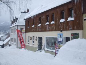 un edificio cubierto de nieve con un cartel de coca frente a él en Ferienwohnung Familie Kowarik, en Kurort Oberwiesenthal