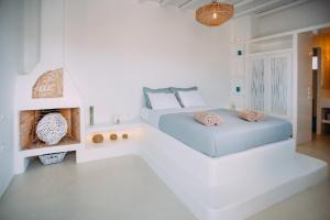 a white bedroom with two beds and a fireplace at Mykonos Supreme Comfort Suites & Villas in Kalafatis
