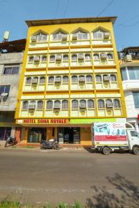 żółty budynek z ciężarówką zaparkowaną przed nim w obiekcie Hotel Sona w mieście Panaji