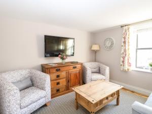 a living room with two chairs and a tv at Foundry Cottage in Norwich
