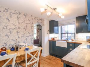 a kitchen with blue cabinets and a wooden table at Foundry Cottage in Norwich