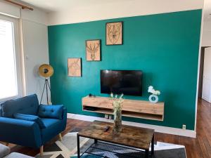 a living room with a blue couch and a television at T3 spacieux & cosy, climatisé, très proche Loire in Orléans