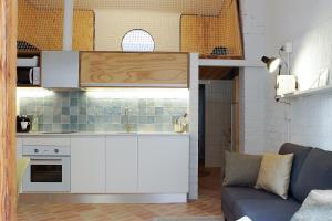 cocina con armarios blancos y sala de estar con sofá en Casa Gall4, en Elche