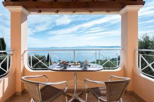 Corfu Shell Apartments في برباتي: شرفة مع طاولة وكراسي أمام النافذة
