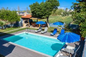 an outdoor swimming pool with umbrellas and chairs at Spyros Villa Apartments in Adelianos Kampos