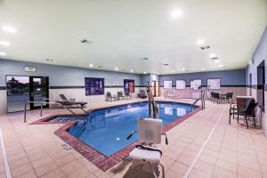 una piscina en un hotel con sillas y mesas en Holiday Inn Express and Suites Pryor, an IHG Hotel, en Lusta