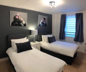 um quarto com duas camas e duas fotografias na parede em GRAPHITE APARTMENTS em Inverness