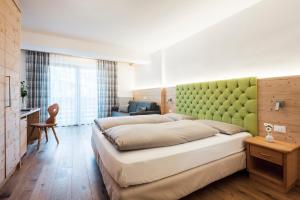 a bedroom with a large bed with a green headboard at Piccolo Hotel Claudia No Pets in San Vigilio Di Marebbe