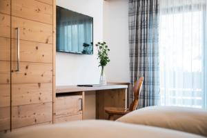 een slaapkamer met een bureau en een televisie in een kamer bij Piccolo Hotel Claudia No Pets in San Vigilio Di Marebbe