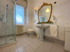 een badkamer met een wastafel, een toilet en een spiegel bij Villa Alda Suites & Rooms in Cervia +36 foto's
