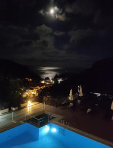 a pool at night with the moon in the sky at Petrino Apartments in Parga