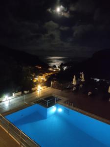 una piscina por la noche con luna llena en Petrino Apartments, en Parga