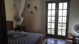 ein Schlafzimmer mit einem Bett und einem großen Fenster in der Unterkunft Casa piscina, mar e lagoa in Araruama + 22 Fotos