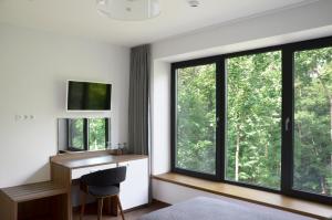 a bedroom with large windows and a desk with a computer at Tip Tap Guest House in Druskininkai