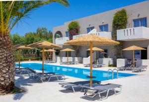 a hotel with a swimming pool with chairs and umbrellas at Akti Beach Club in Kardamaina