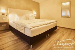 a large bed in a bedroom with a wooden floor at Kampowski Apartments Deluxe in Bad Nauheim
