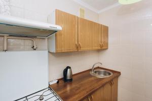 Elle comprend une petite cuisine avec un évier et des placards en bois. dans l'établissement Premium Home, à Soumy