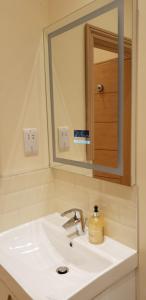 a bathroom sink with a mirror and a soap dispenser on it at London Luxury Apartments 5 min walk from Ilford Station, with FREE PARKING FREE WIFI in Ilford