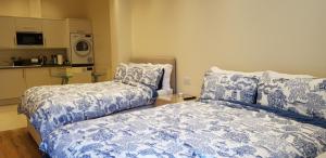 a bedroom with two beds with blue and white sheets at London Luxury Apartments 5 min walk from Ilford Station, with FREE PARKING FREE WIFI in Ilford