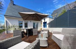 une terrasse avec une table, des chaises et un parasol dans l'établissement La villa Ty Mor Braz, à Plouarzel