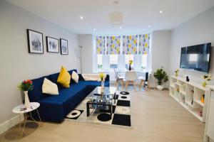 een woonkamer met een blauwe bank en een tafel bij Morden Central Self Contained Flat by CozyNest in Reading