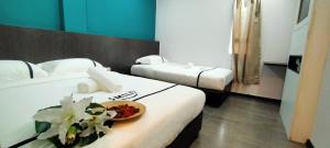 a hotel room with two beds and a bowl of flowers at Smile Hotel Petaling Jaya SS2 in Petaling Jaya