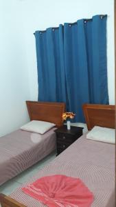 2 Betten in einem Zimmer mit blauen Vorhängen in der Unterkunft Sua Casa na Praia da Costa 10 Esta Tem Ar Condicionado Internet 2Q Completa Geladeira Fogao TV Centro in Vila Velha
