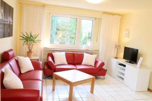 a living room with a red couch and a tv at Ferienwohnungen Domblick-Herkenrath in Bergisch Gladbach
