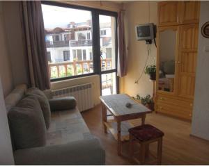- un salon avec un canapé, une table et une fenêtre dans l'établissement Guest House Antoaneta, à Nessebar