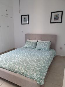 a bedroom with a bed with a green comforter and pillows at Central Gem - 10 min walk to the sea, harbor and mall in Paphos City